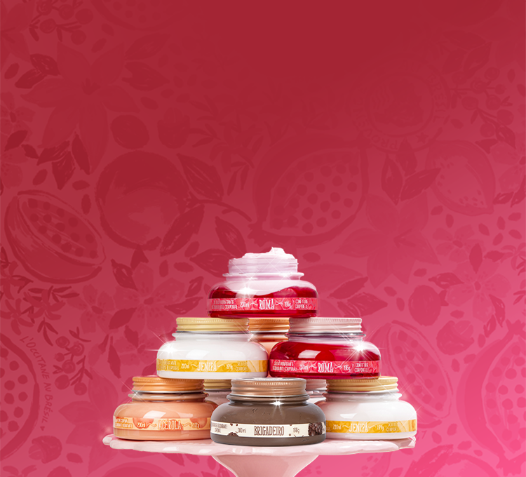 A imagem mostra uma pilha de potes de cremes em uma base branca, com diferentes fragrâncias, como "ROMÃ", "COCO" e "JENIPAPO", sobre um fundo rosa vibrante com desenhos de romã. Ao lado, há um texto em branco e rosa, escrito "Vem EMPREENDER COMIGO, mon amour!".